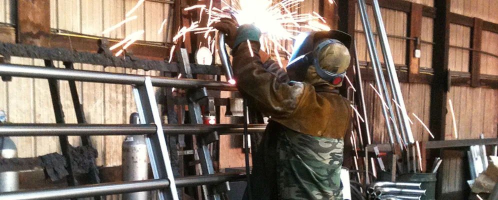 A Heritage Gate fabricator welding a steel farm gate in the shop
